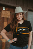 Female model wearing our Meter Tee. Shirt is Black with white and orange lettering that says The Next Waltz, Austin TX, Sound Recordings 