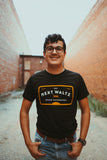 Male model wearing our Meter Tee. Shirt is Black with white and orange lettering that says The Next Waltz, Austin TX, Sound Recordings 
